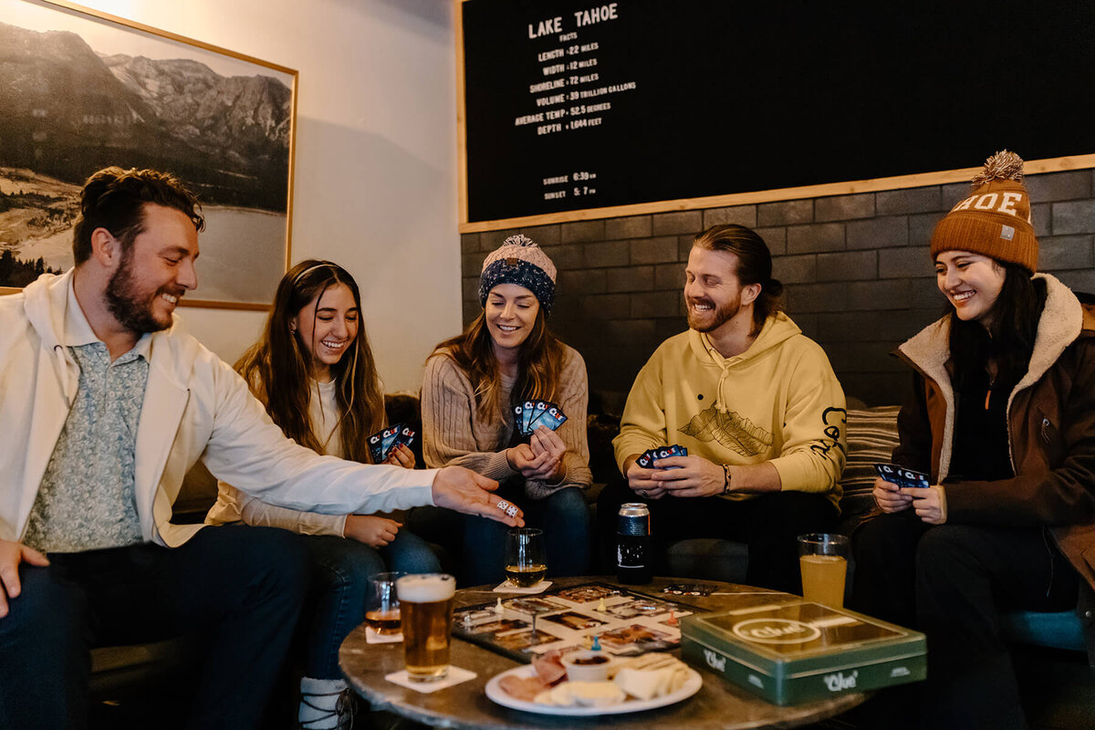 A group of five people playing a game at a table in a bar.